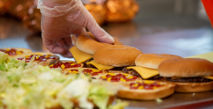 A crew member assembles hamburgers with toppings at Dick's Drive-In.